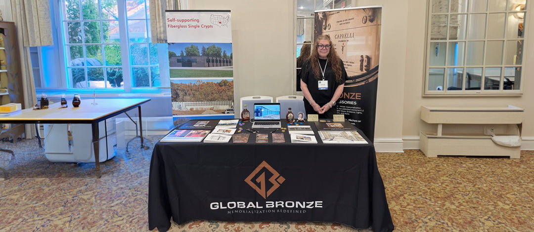 Person standing behind a table with a Global Bronze brand display at an event