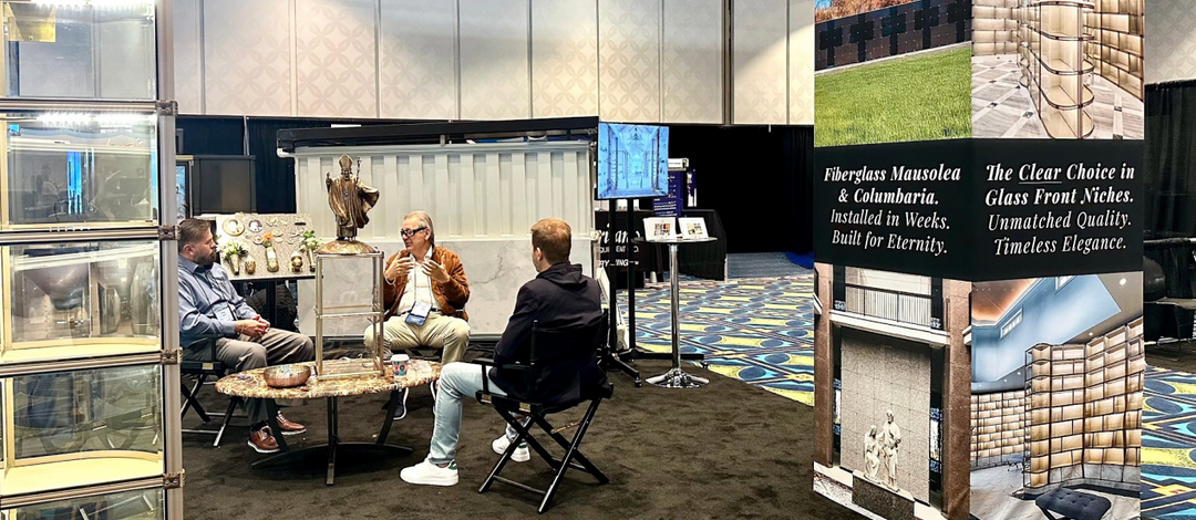 People interacting at a trade show booth with promotional materials GFN and The EZ-Mausolea system in the background
